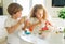 Two siblings brother and sister toddler boy tween girl painting easter eggs on kitchen at home on the spring sunny day