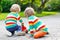 Two siblings, kid boys playing with red school bus