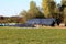 Two silage piles of fermented high moisture stored fodder covered with thick nylon and used car tyres with hay bales wrapped in