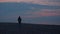 Two silhouettes against the backdrop of the sea and sunset. A male silhouette runs after the birds on a sunset