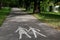 Two silhouettes of a woman and a child on an empty footpath in a park. Parental Guidance Concept - Pedestrian Sign On The Pavement