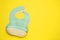 Two silicone baby bibs on yellow background, top view. Space for text