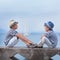 Two similar brother sitting on waterfront,