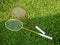 Two simple colorful badminton rackets laying on the grass, closeup, nobody. Leisure, sports recreation equipment symbol