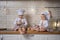 Two sisters in cook hats are sitting on the kitchen table in the evening and eating cookies with tea