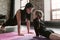 Two sisters of different age wearing black sports clothes working-out together in a flat with loft interior