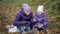 Two sisters drink cocoa with marshmallows in the autumn park