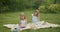 two sisters with long hair they draw in a notebook and relax in a green park