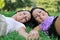 Two sisters lying outdoors in grass holding hands