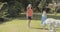 Two sisters playing with a dog outdoors on the grass