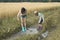 Two sisters in rain boots playing in puddle of rainwater