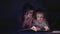 two sisters reading a book with a flashlight in a dark room at night