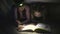 Two sisters reading a book under a blanket with a flashlight in a dark room at night