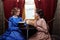 Two sisters in retro dress reading books in train compartment