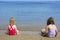 Two sisters sit on beach bathing suit swimsuit