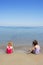 Two sisters sit on beach bathing suit swimsuit