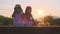 Two sisters sit on the tracks and take selfies together with their smartphones at sunset. Asian sisters enjoy spending time togeth