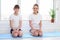 Two sisters are sitting at home on a sports mat before training