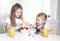 Two sisters sitting at kitchen table eating fruits.Healthy nutrition concept.Vitamin food.Children have a lunch.Frendship