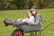 Two Sisters Sitting In Wheelbarrow