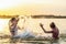 Two sisters splashing water playing in the lake at sunset background