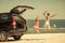 Two sisters standing near a car on the beach