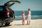 Two sisters standing near a car on the beach