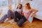 Two sisters using their smartphones sitting on floor near bed