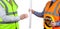 Two site surveyors in high visibility vests handing over site pl