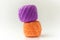 Two skeins of thread in purple and orange. Knitting threads on a white background