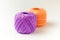 Two skeins of thread in purple and orange. Knitting threads on a white background