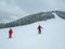 Two skiers, a man and a woman, in red clothes on a ski Track in mountainside