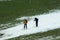 Two skiers putting on skis at the bottom of a ski slope