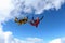 Two skydivers in color suits are falling in the clouds.