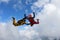 Two skydivers in color suits are falling in the clouds.