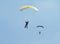 Two skydivers with colourful chutes approaching landing area in