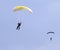 Two skydivers with colourful chutes approaching landing area in