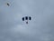 Two skydivers in the sky with colorful parachutes on a blue sky background