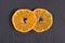 Two slices of mandarin lies on black slate. Concept of healthy, organic, vegan food, vitamins. Top view. Fresh orange, tangerine b