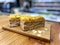 Two slices of Napoleon cake with mango on top, on a wooden board. Cafe Style Concept