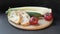 Two slices of white beautiful airy white bread, fresh vegetables - cucumbers, tomatoes and celery, all on a round wooden cutting