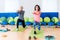 Two slim Caucasian women exercising on mats doing lunges with arms out in front of them in fitness club