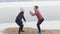 Two slim women in jackets doing squats on the snowy beach