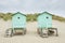 Two small beach houses with steps on a sandy beach against the d
