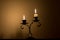 Two small candles on holder over melted wax, in dark