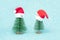 Two small Christmas trees in a red Santa Hats. Decorating of Artificial Fir tree. Beautiful imitation of a mini