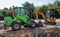 Two small excavators on a large construction site. Bright green on wheels and yellow on tracks. Earthworks and construction.