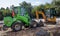 Two small excavators on a large construction site. Bright green on wheels and yellow on tracks. Earthworks and construction.