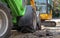 Two small excavators on a large construction site. Bright green on wheels and yellow on tracks. Earthworks and construction.