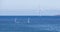 Two small lateen sailboats sail near an offshore wind turbine on the island of Gran Canaria